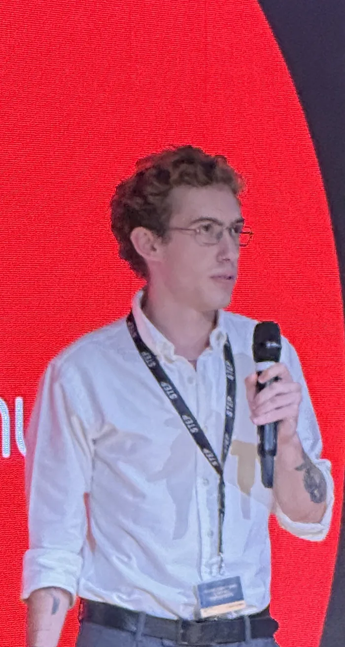 João Balen presenting a project on stage with a microphone